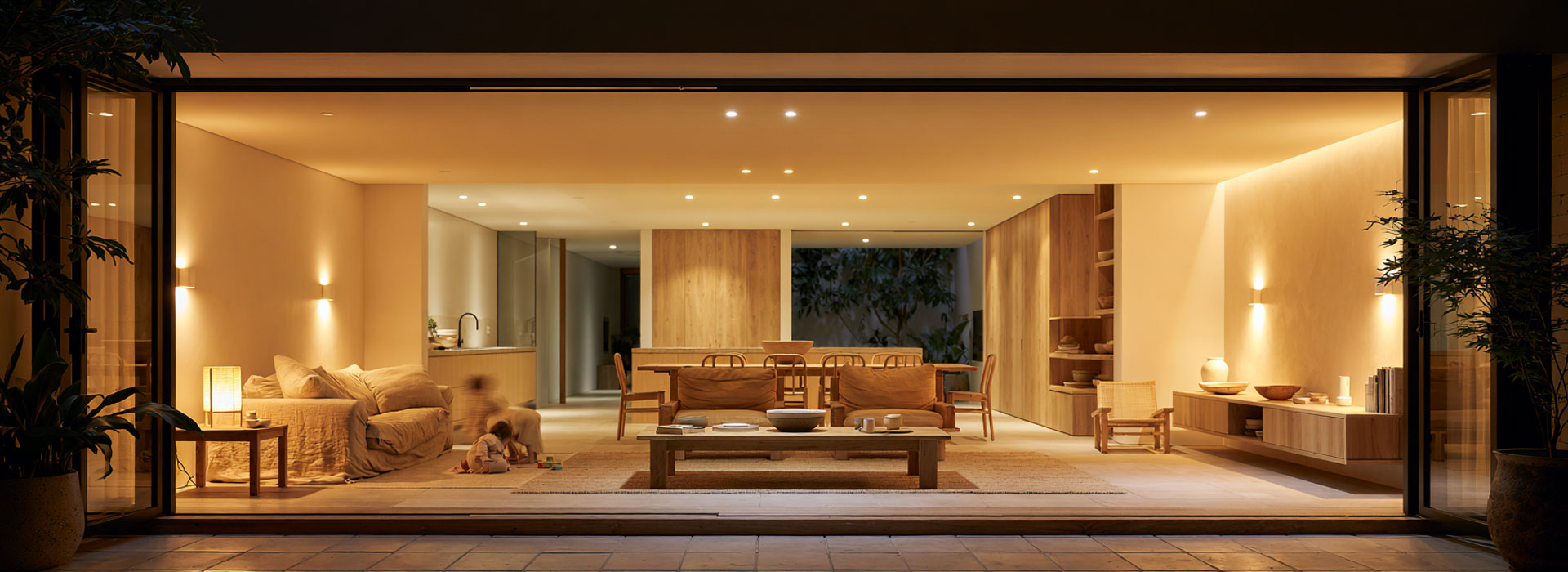 architectural editorial photograph of a beautifully renovated Sydney terrace home interior at early evening, contemporary Australian living and dining area with warm layered LED lighting switched on, ceiling lights, wall lights and soft practical lighting creating different zones, accurate understated electrical fitting, natural timber, simple Australian furnishings, subtle signs of everyday family life, calm welcoming atmosphere, professional residential electrical upgrade