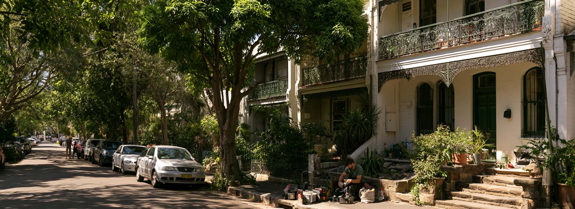 Sydney electrician working outside a classic Annandale terrace house, leafy Inner West street, Victorian and Federation homes, iron lace balcony, sandstone steps, neat tools, Australian cars, natural daylight